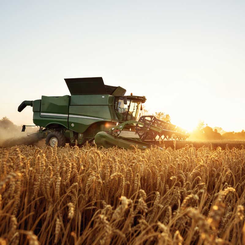 Combine harvester in farming operation, showcasing LubeLine lubricants for agricultural machinery